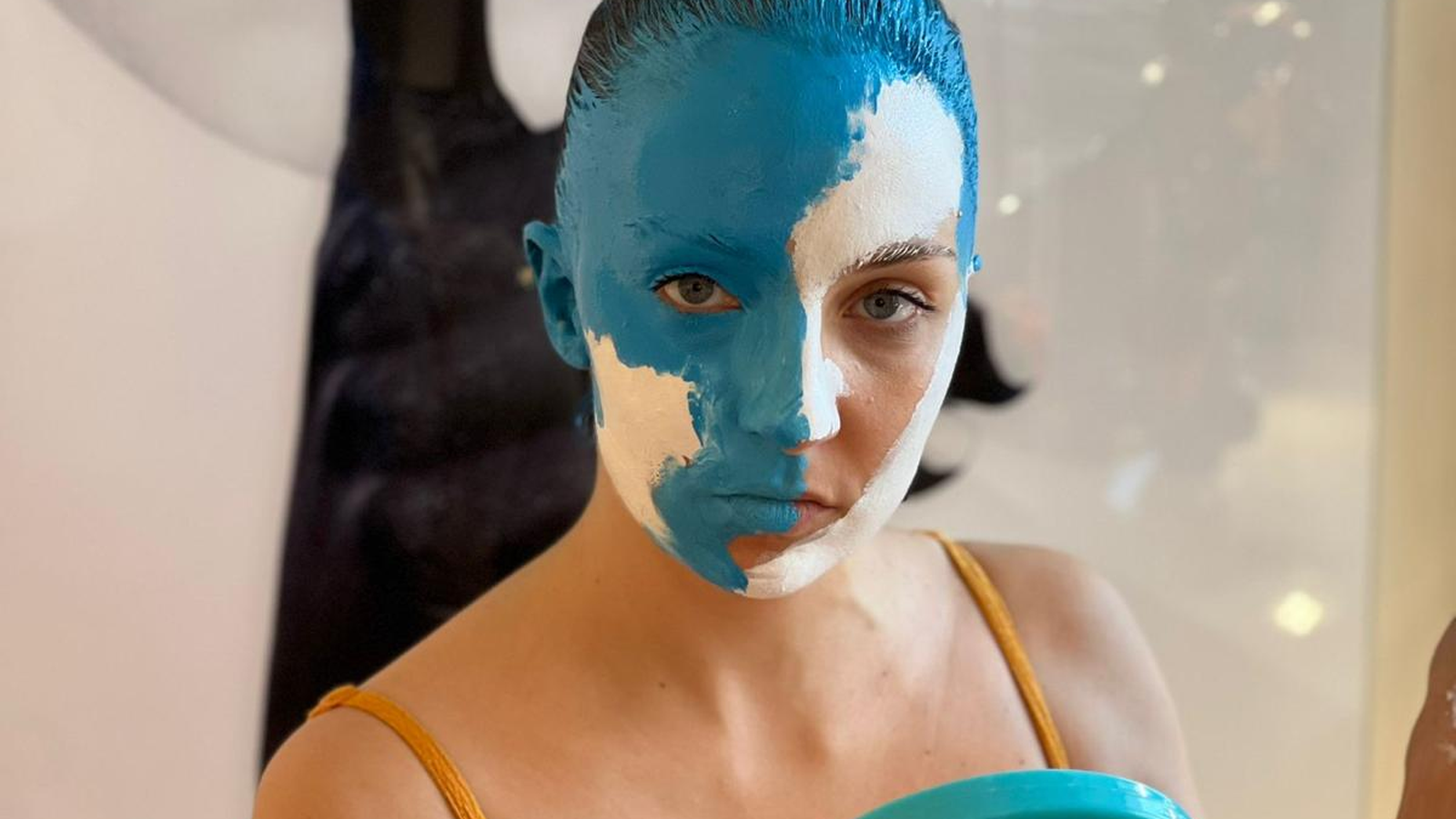 Artist with half of the face painted blue, part of Elvira Carrasco's artistic project